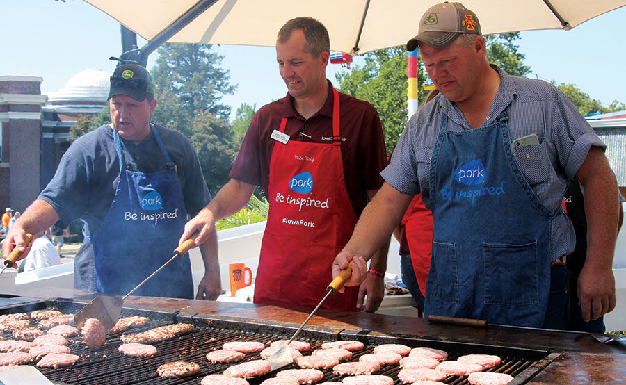 Iowa Secretary of Agriculture Mike Naig (center) takes a turn at the grill in the pork tent. Joining Naig are Cass County pork producers Mike Decager and Terry Aupperle.